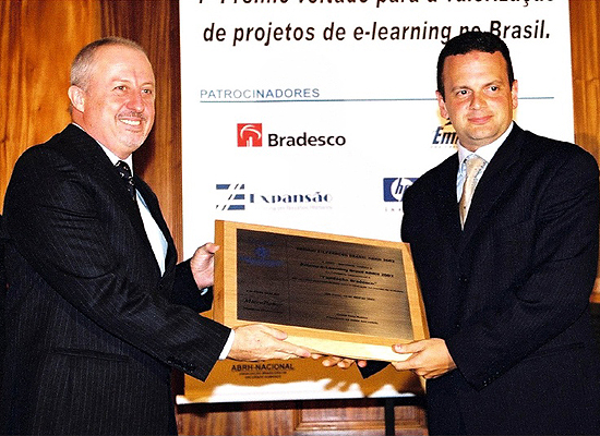 Evaldo Bazeggio da Caixa Econômica Federal recebe o Prêmio e-Learning Brasil ABRH 2002 de Antônio Salvador, Diretor da Promon e ABRH.